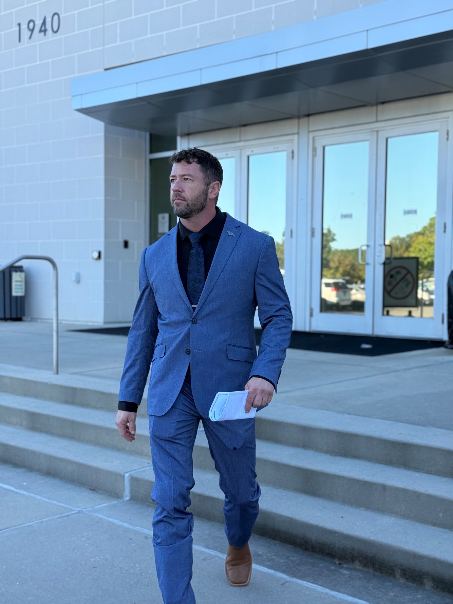 Jordon Bowen in a blue suit carrying documents outside a building